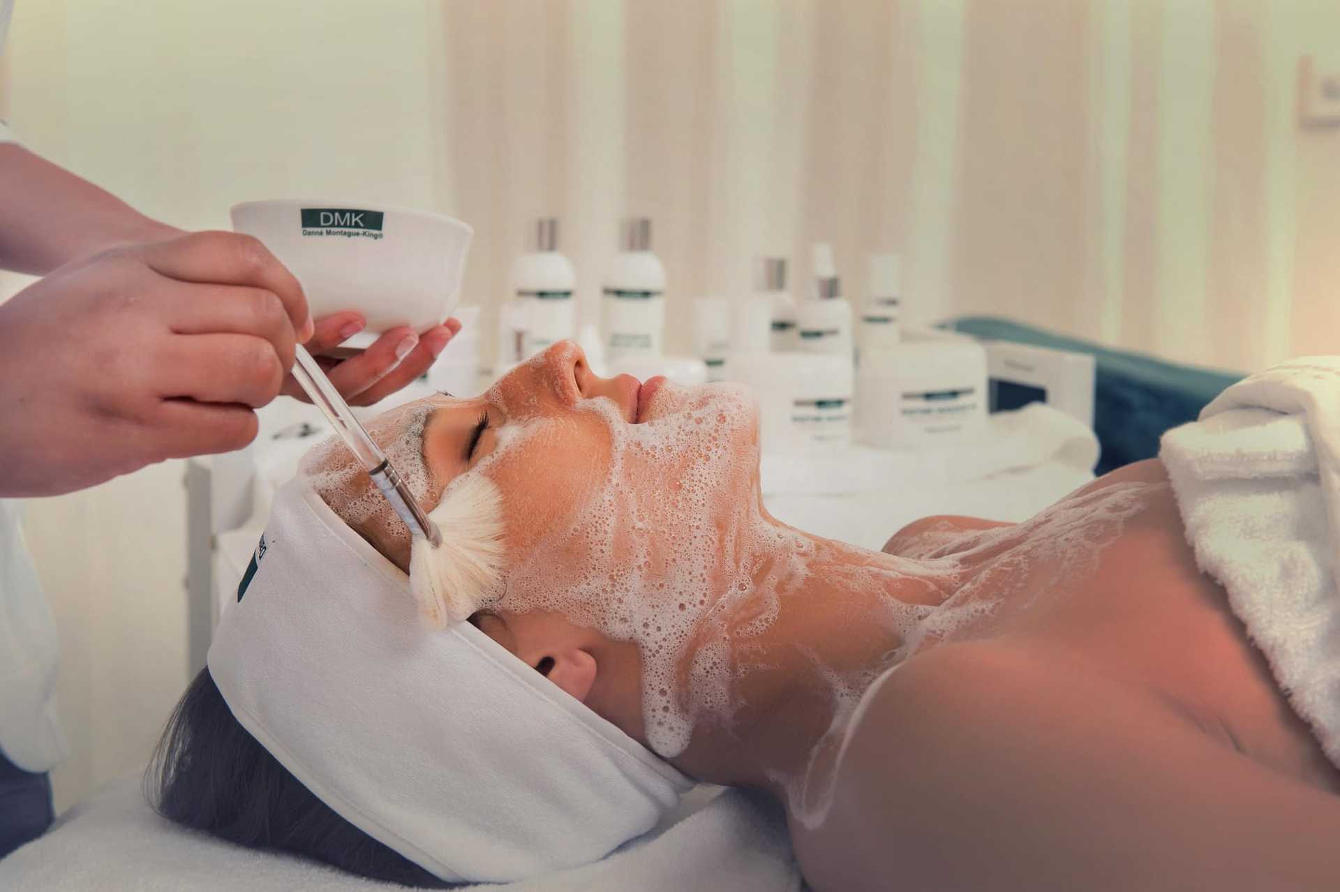 Facial treatment in spa setting with foam mask applied to a woman’s face.