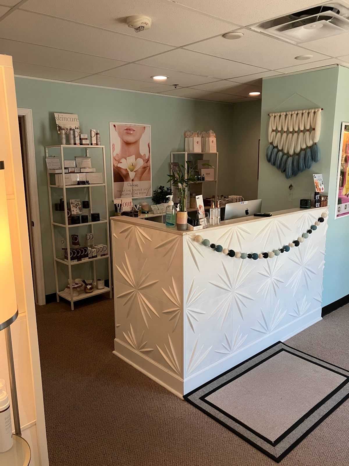 Reception desk in a modern skincare clinic with products and soft green walls.