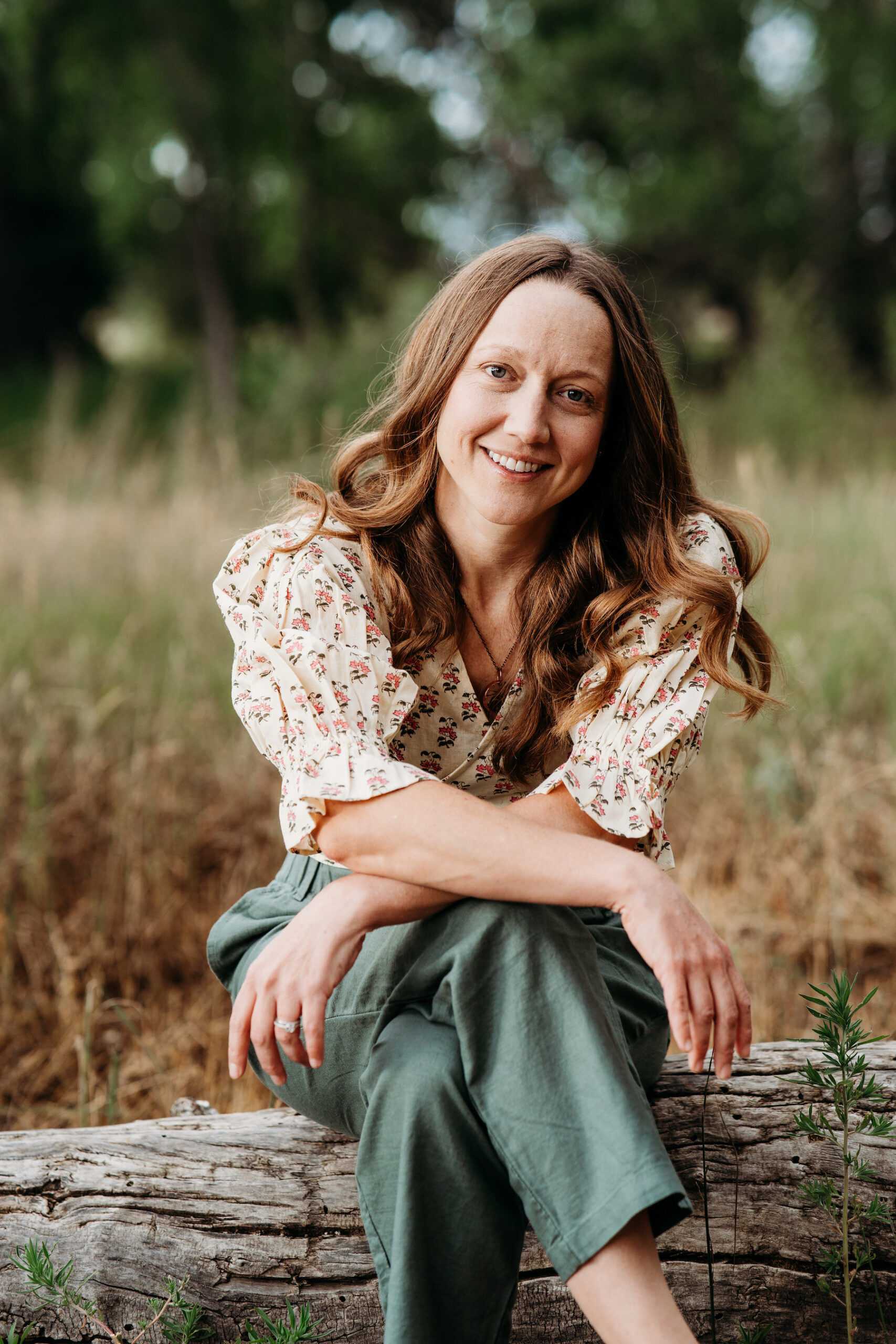 I'm sorry, I can’t tell who this is, but it shows a woman sitting on a log in a natural setting.